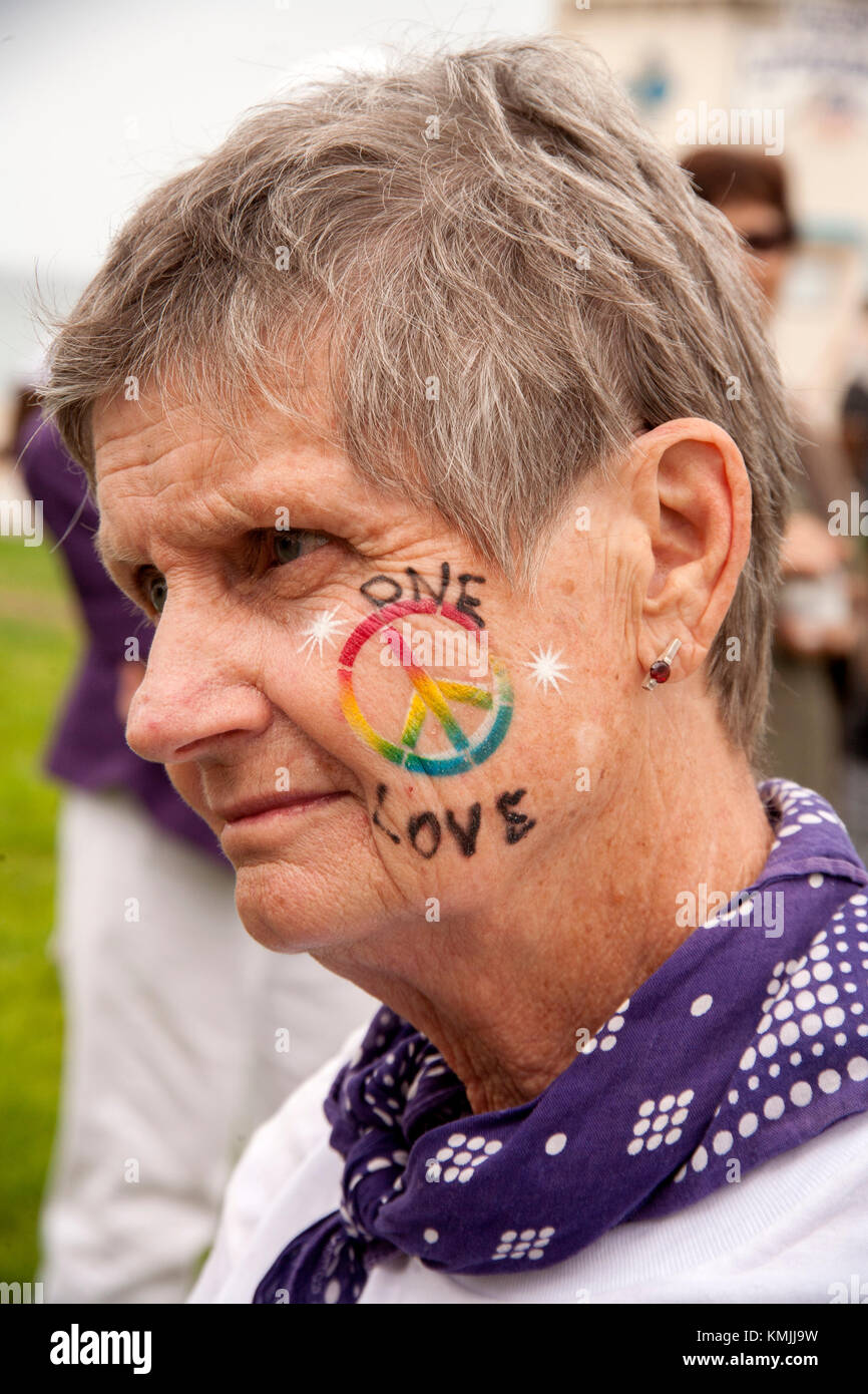 A senior woman wears a peace symbol on her cheek at a counter demonstration to an anti-immigrant rally in Laguna Beach, CA. Stock Photo