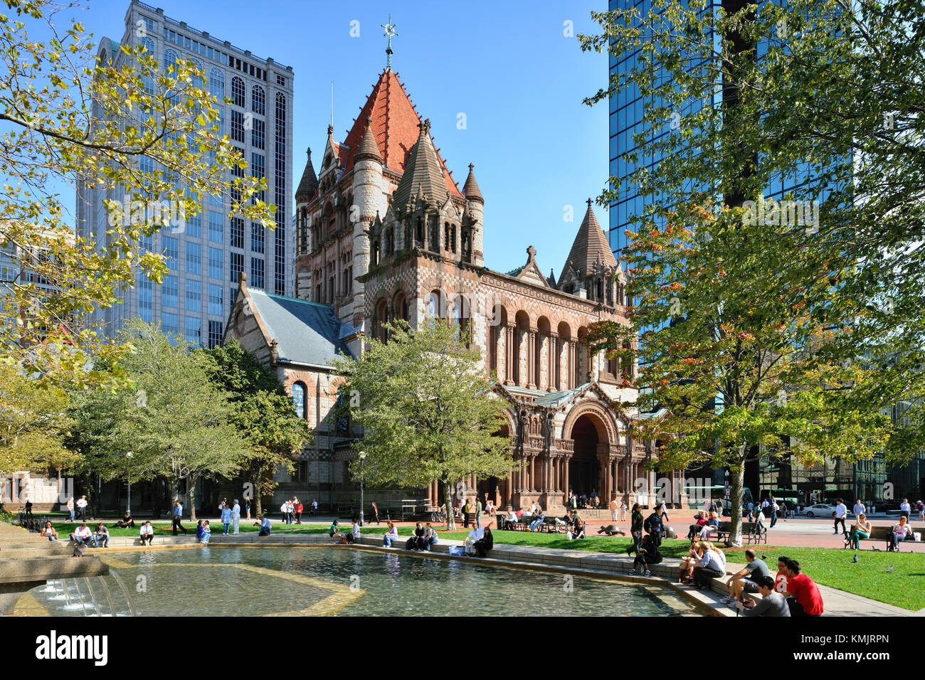 Trinity Church, a national historic landmark building in Back Bay, Boston.  People hanging around the Copley Square fountain in a sunny day of fall. Stock Photo