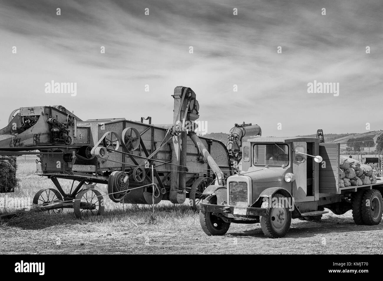 McMinnville, Oregon, USA - August 13, 2016:  Black and white of an old flat bed truck parked by an old grain harvester. Stock Photo