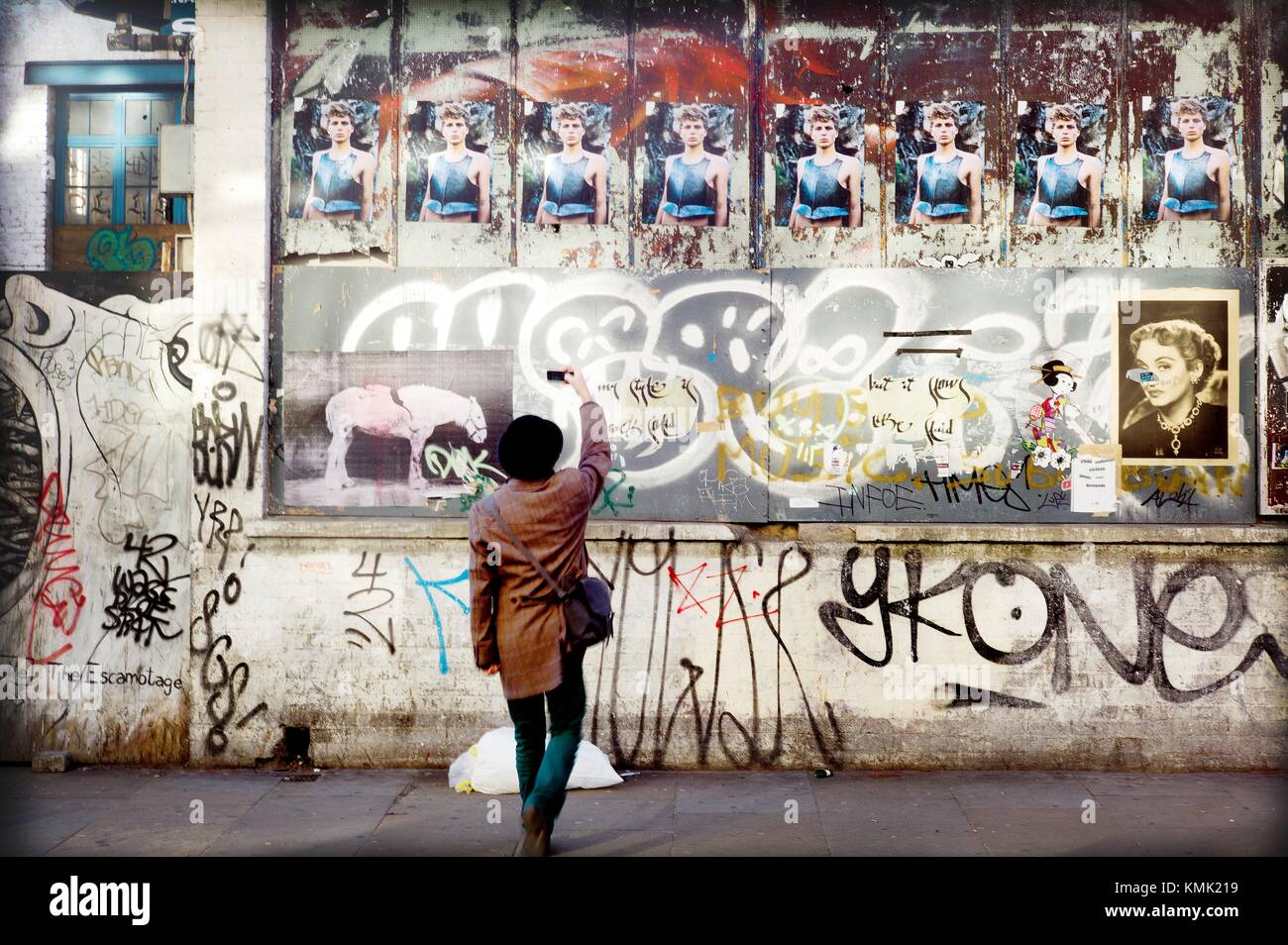 Man taking picture of a graffiti on wall. East London, London, England Stock Photo