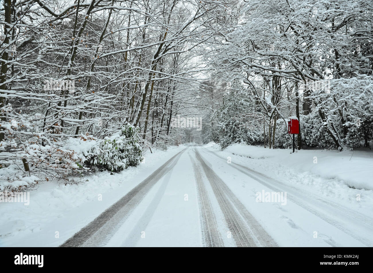 Picturesque wintry scene in Farnham, south of England with a snowy lane, car tracks and red post box Stock Photo