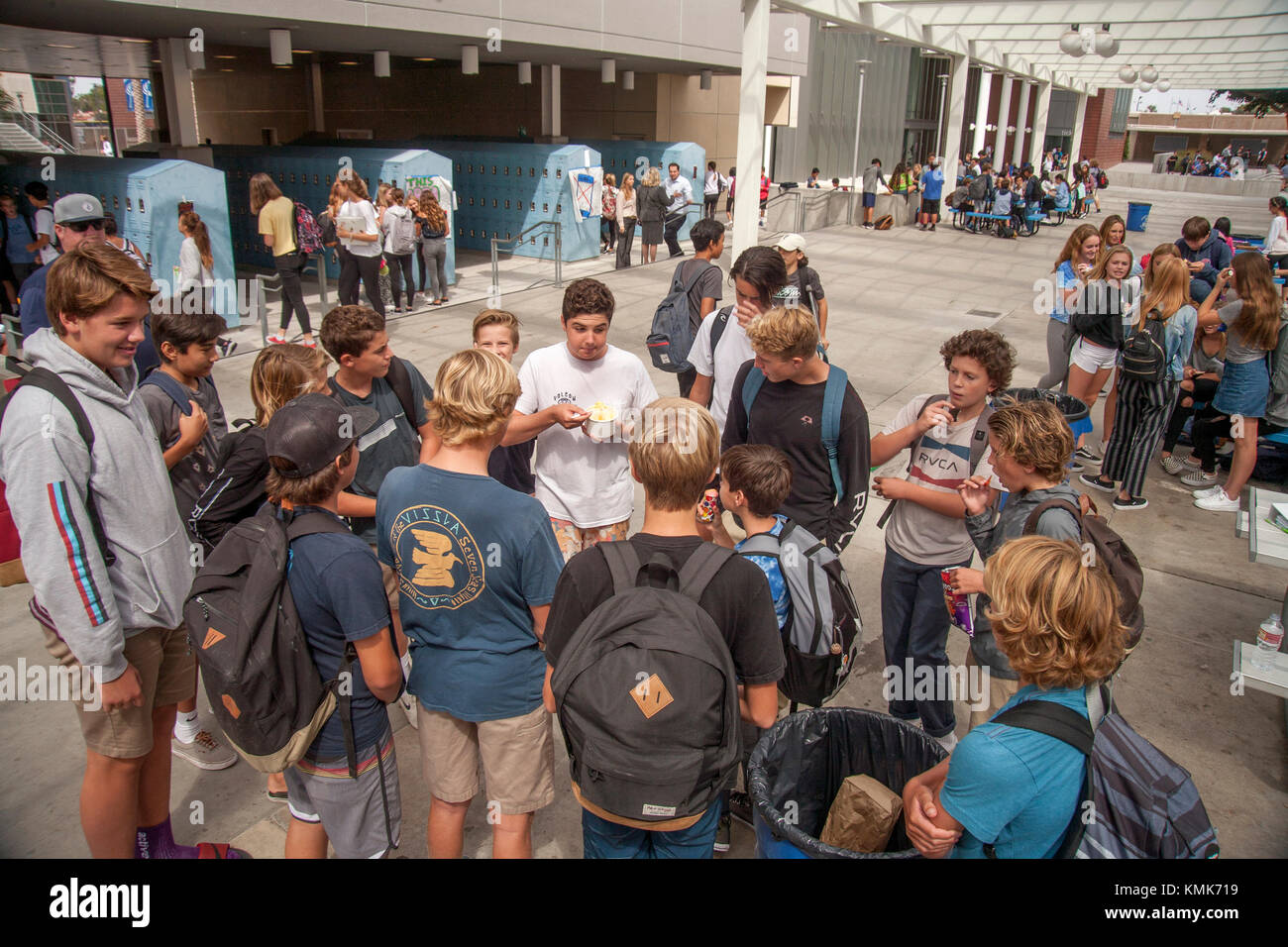 Newport Beach, CA, middle school students converse in a "cell phone free"  yard during recess while one them sneaks the use of a phone anyway. Note  signs in background Stock Photo -