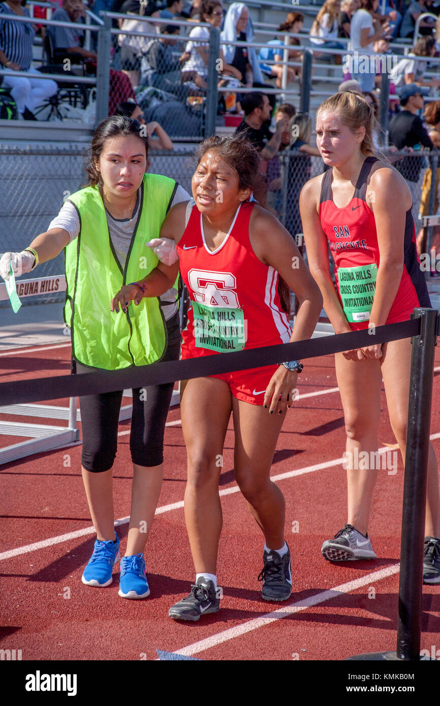 An exhausted Hispanic teen girl athlete gets some help after crossing