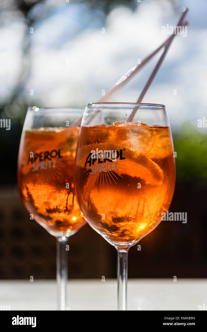 Two glasses of Aperol Spritz, a blend of Aperol, Prosecco and soda water with orange, on a table in an outside bar. Stock Photo