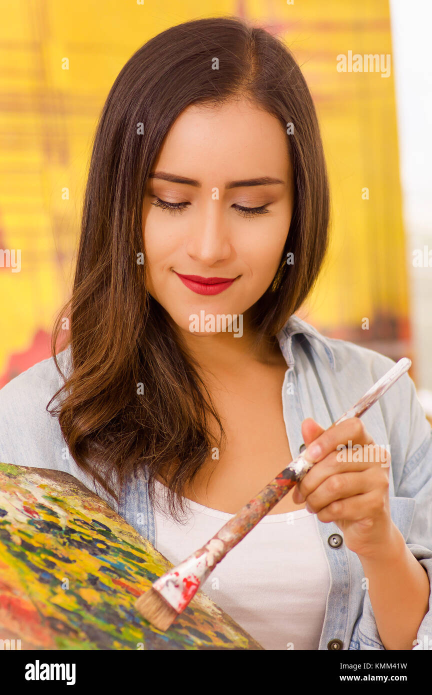 Beautiful young woman painter with color palette and paint brush in ...