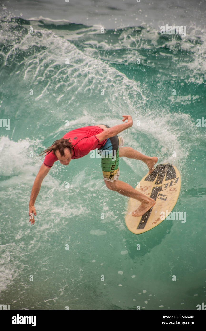 Carefully keeping his balance, a surfer rides the waves on a skimboard