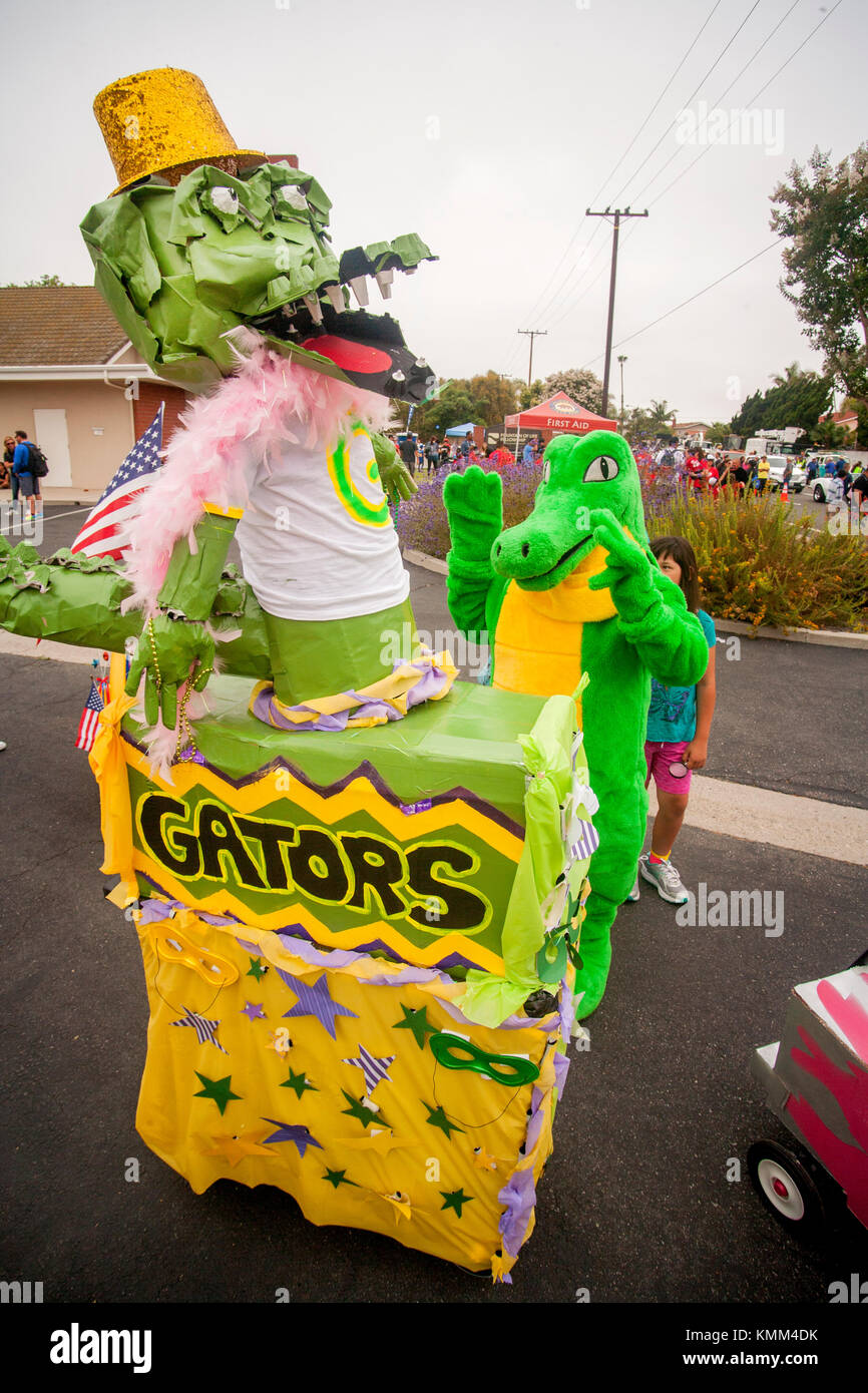 An elementary school's 'Party Gator' float gets some attention from the school 'Gise Gator' in a green reptile costume as they prepare for a city anniversary parade in Fountain Valley, CA. Stock Photo