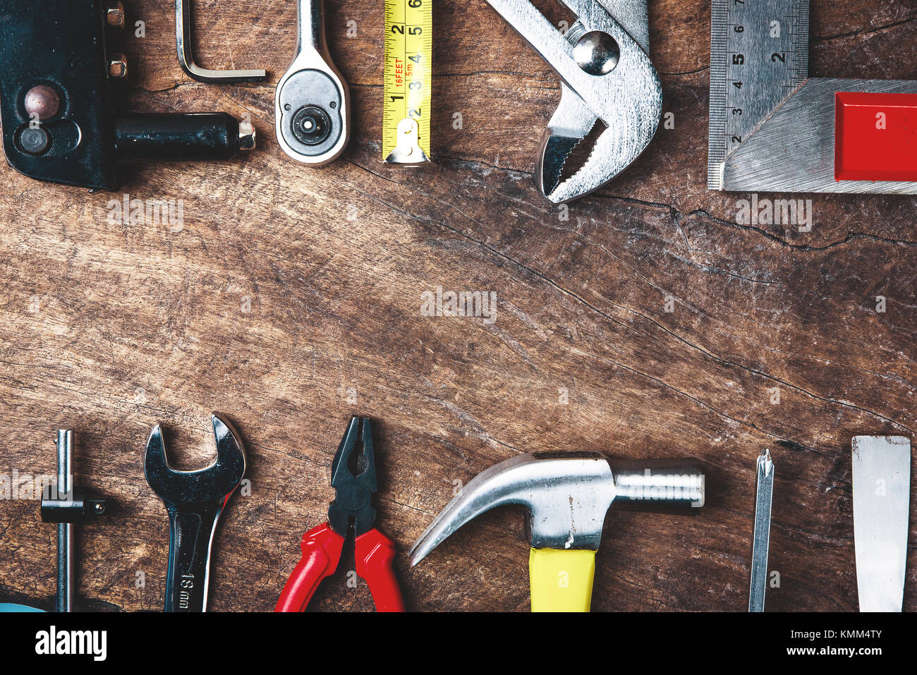 Top view of Working tools,wrench,socket wrench,hammer,screwdriver,plier,electric drill,tape measure,machinist square and safety glasses on wooden back Stock Photo