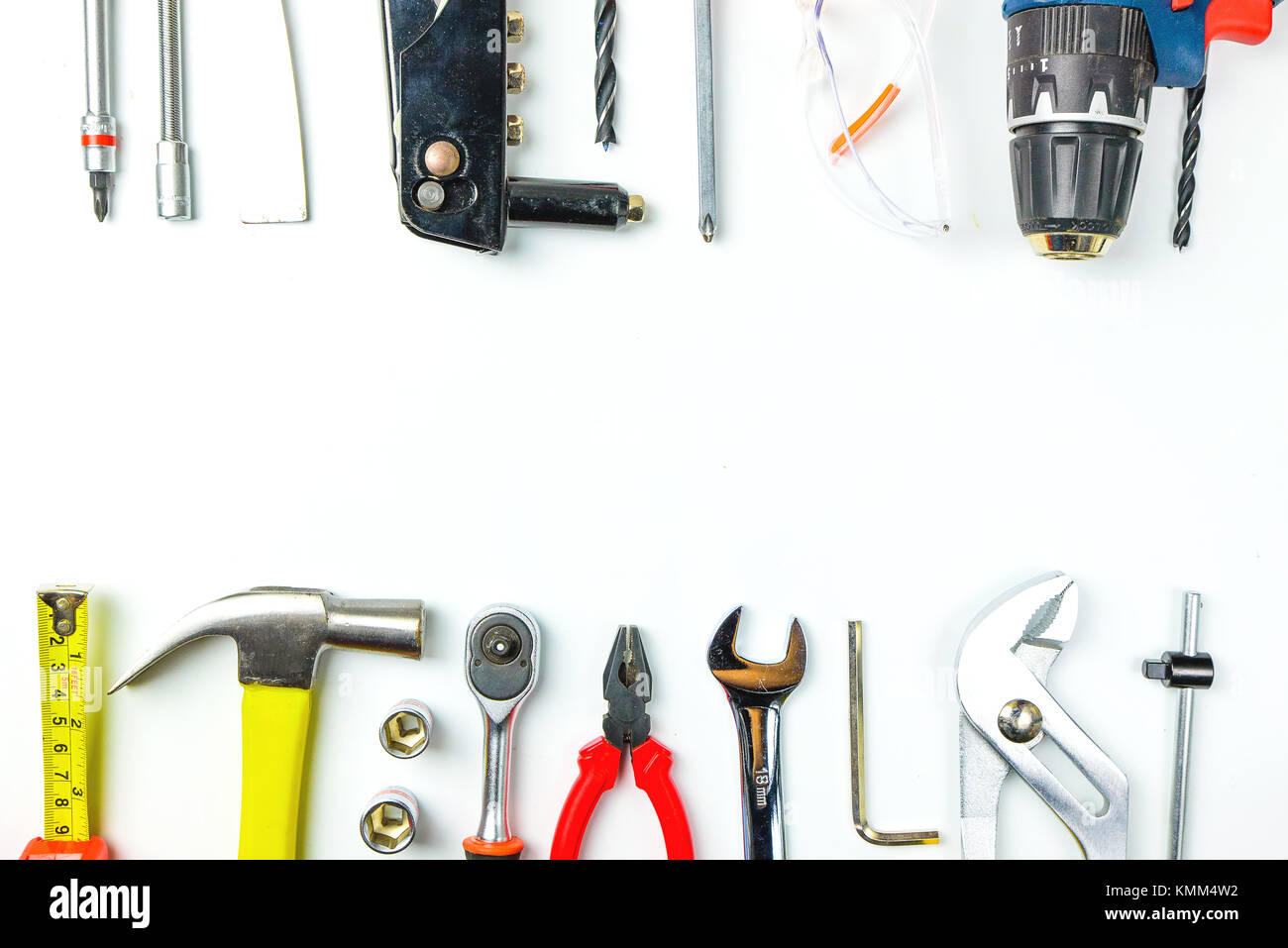 Top view of Working tools,wrench,socket wrench,hammer,screwdriver,plier,electric drill,tape measure,machinist square and safety glasses on white backg Stock Photo