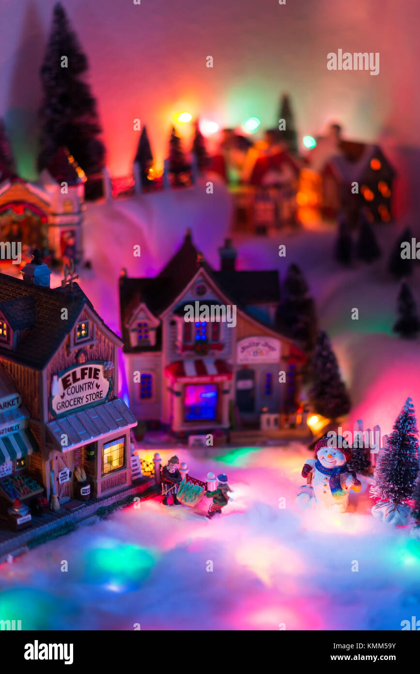 Aerial high perspective view of Christmas times in fairy tale town of elf miniature figurines with happy snowman standing while other two persons stac Stock Photo