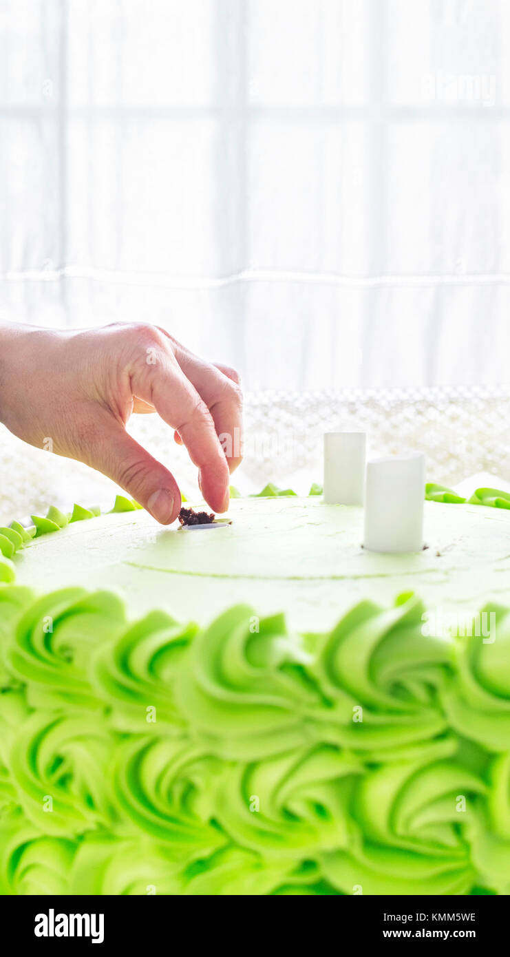 Baker inserting plastic dowels inside green cake. Stock Photo