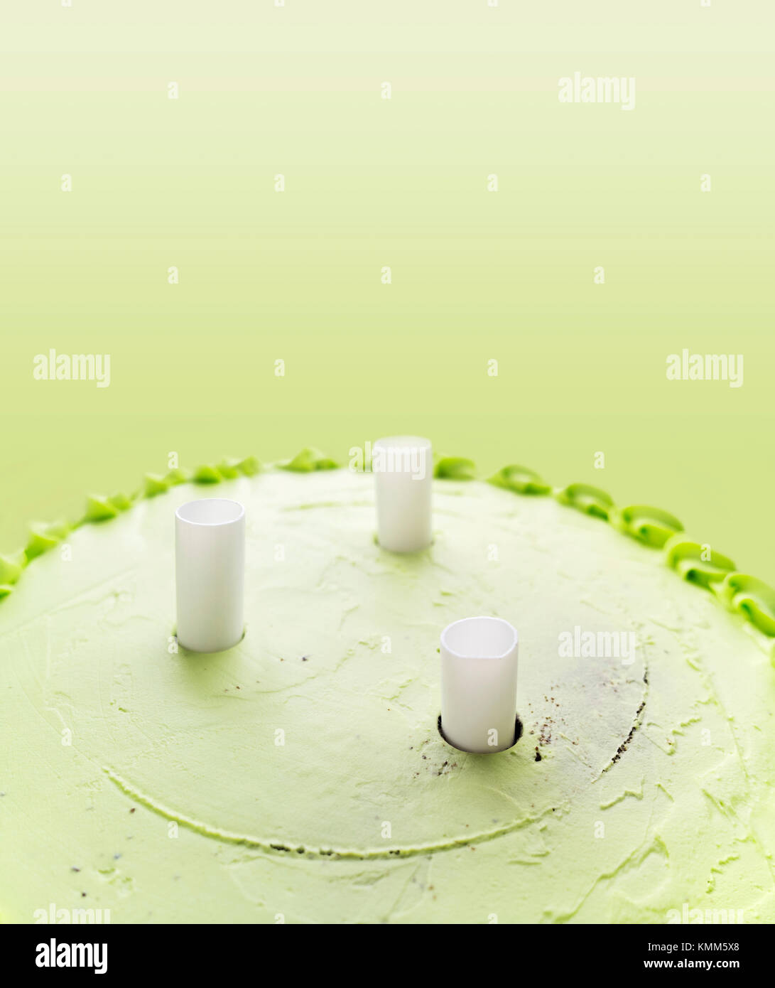 White plastic dowels inside green creamy cake. Stock Photo