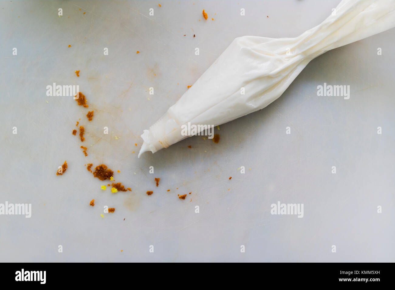 Frosting pastry bag with bread crumbs on cutting mat. Stock Photo