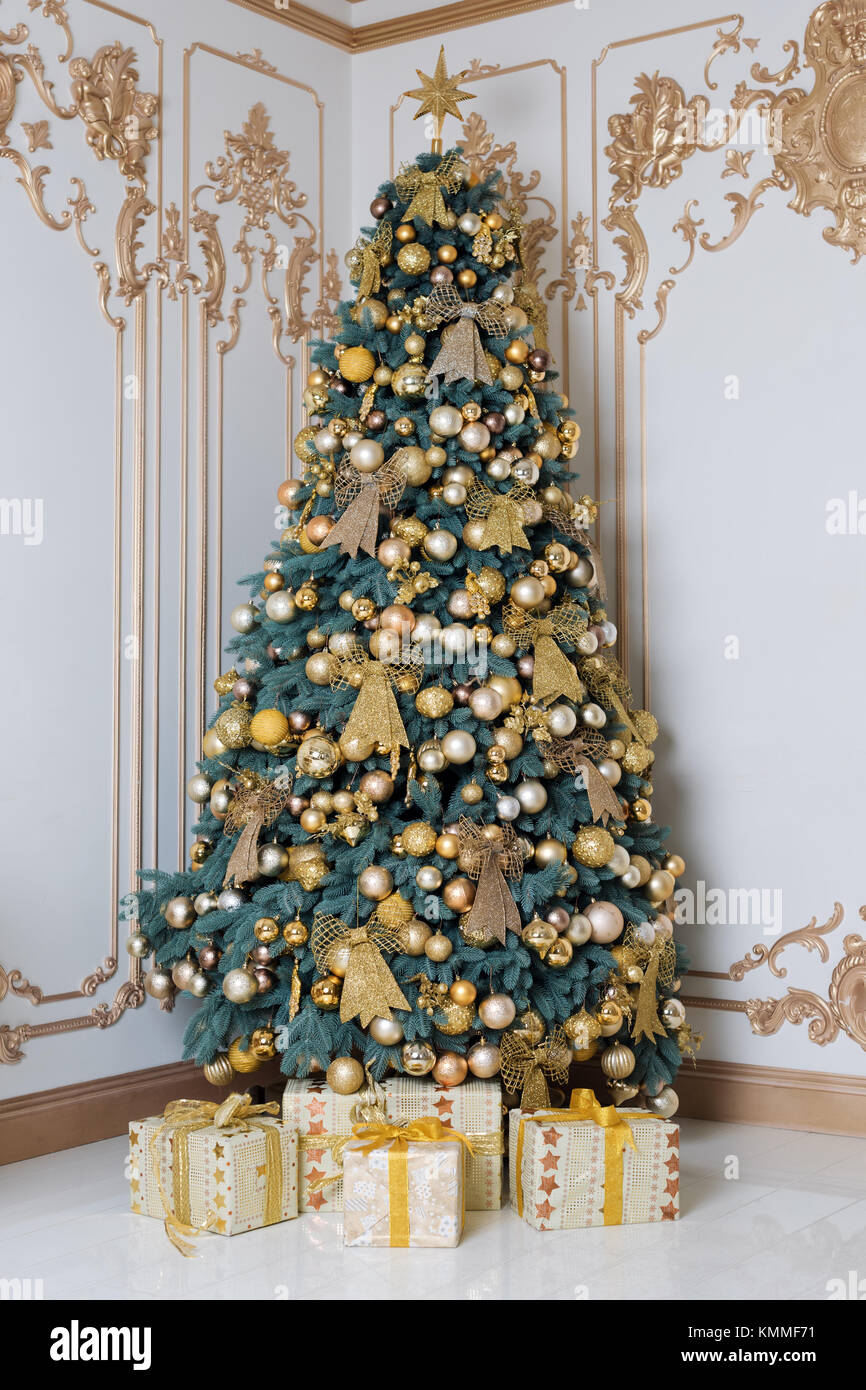 Beautiful decorated golden Christmas tree with present boxes in luxury ...