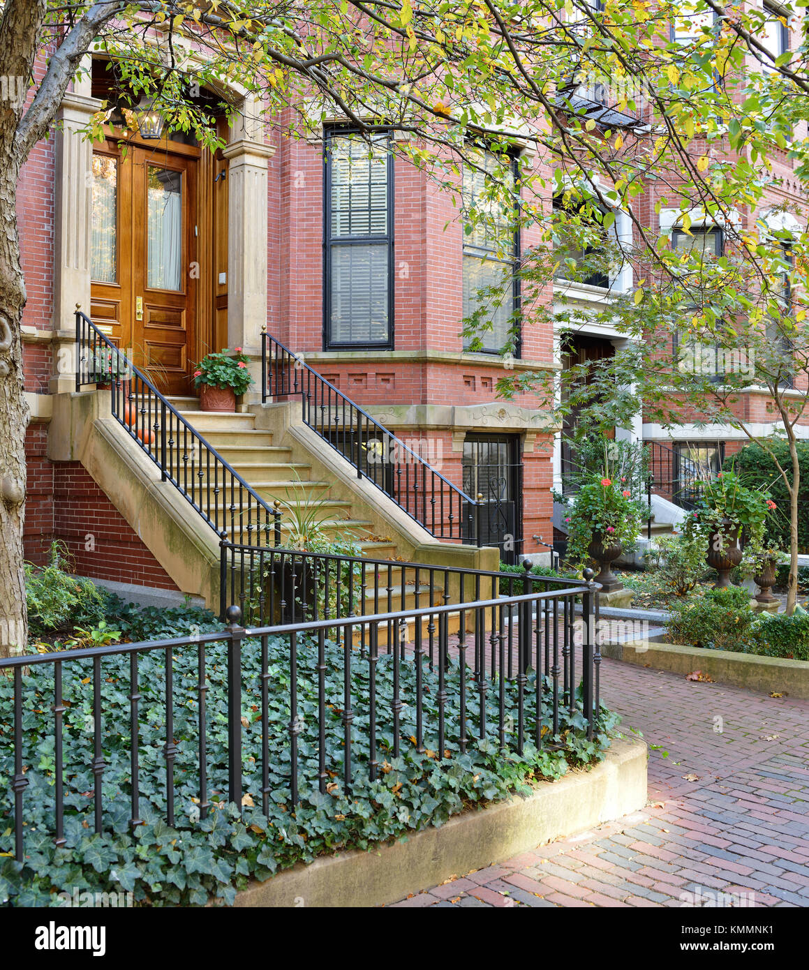 Townhouse apartments in Back Bay, Boston. Brick row houses and sidewalk, cast-iron fence and railings, stone steps, bay windows, garden urns… Stock Photo