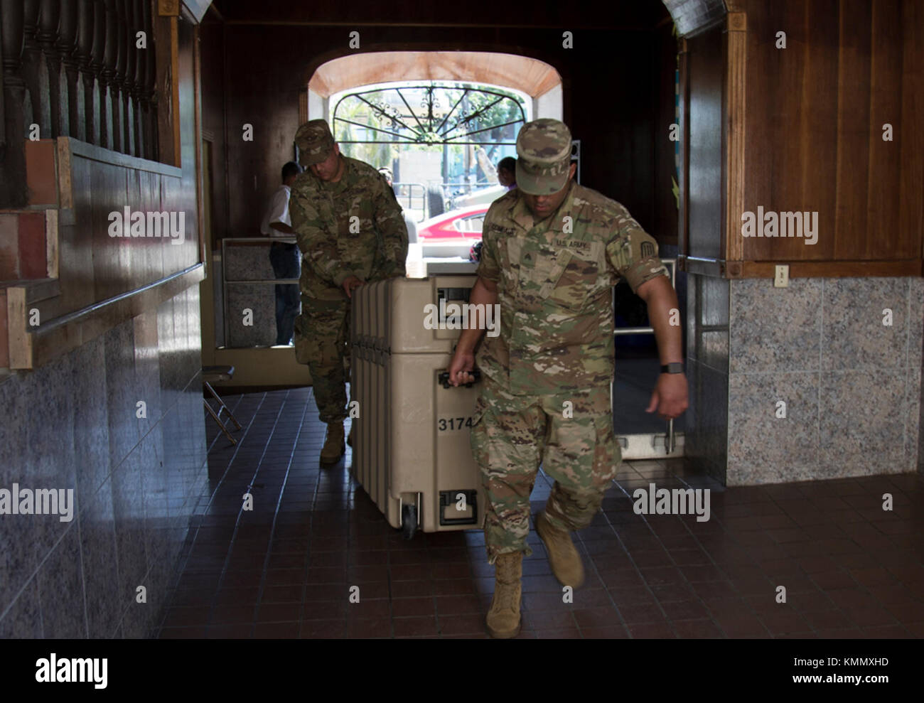 SAN JUAN, Puerto Rico – Army Sgt. Russell Comeaux, a nodal network systems operator-maintainer, and Pfc. Issac Benavidez, an information technology specialist, carry a satellite communications system into the military police headquarters in Vieques, Puerto Rico on Dec. 1, 2017.  Soldiers brought the system to the island to enhance communications between Army units stationed on Vieques and those back on mainland Puerto Rico.  (U.S. Army Stock Photo