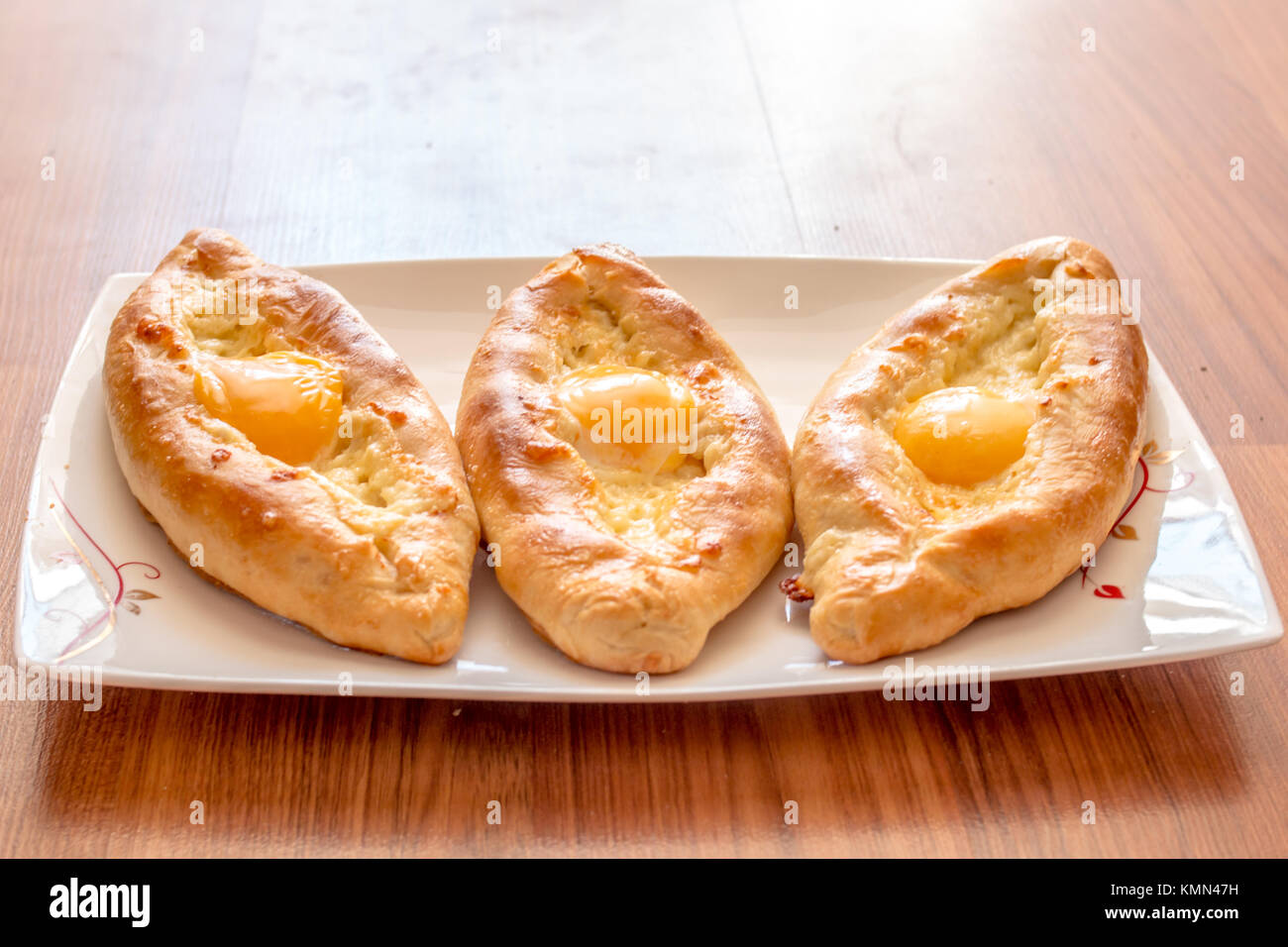 Khachapuri Ajarian on plate. Open pie with mozzarella and egg. Stock Photo