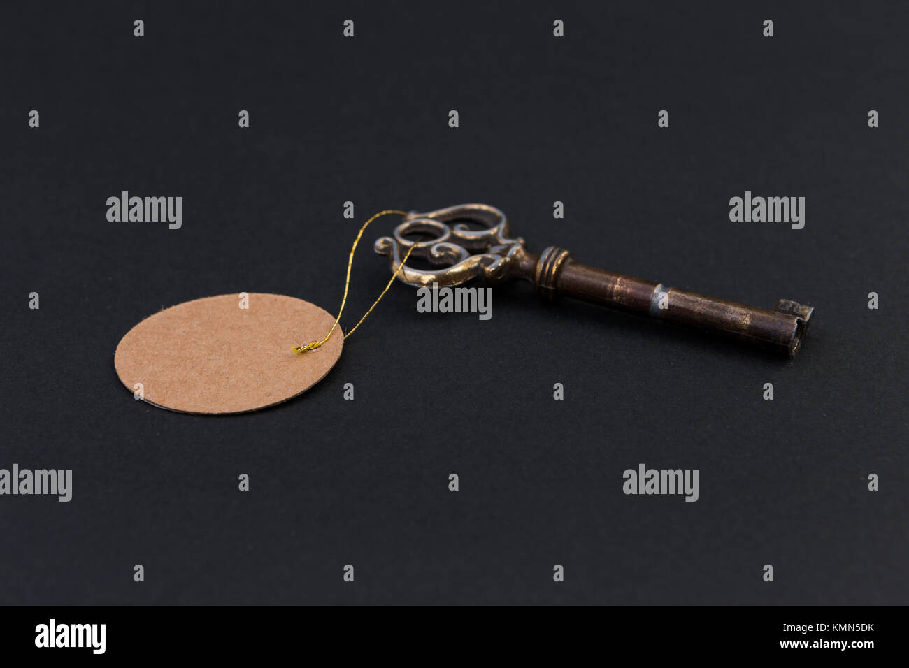 Old house key with blank tag or label on black background Stock Photo