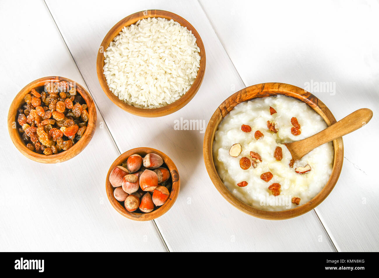 Rice milk porridge with nuts and raisins in wooden bowls on a white wooden table Stock Photo