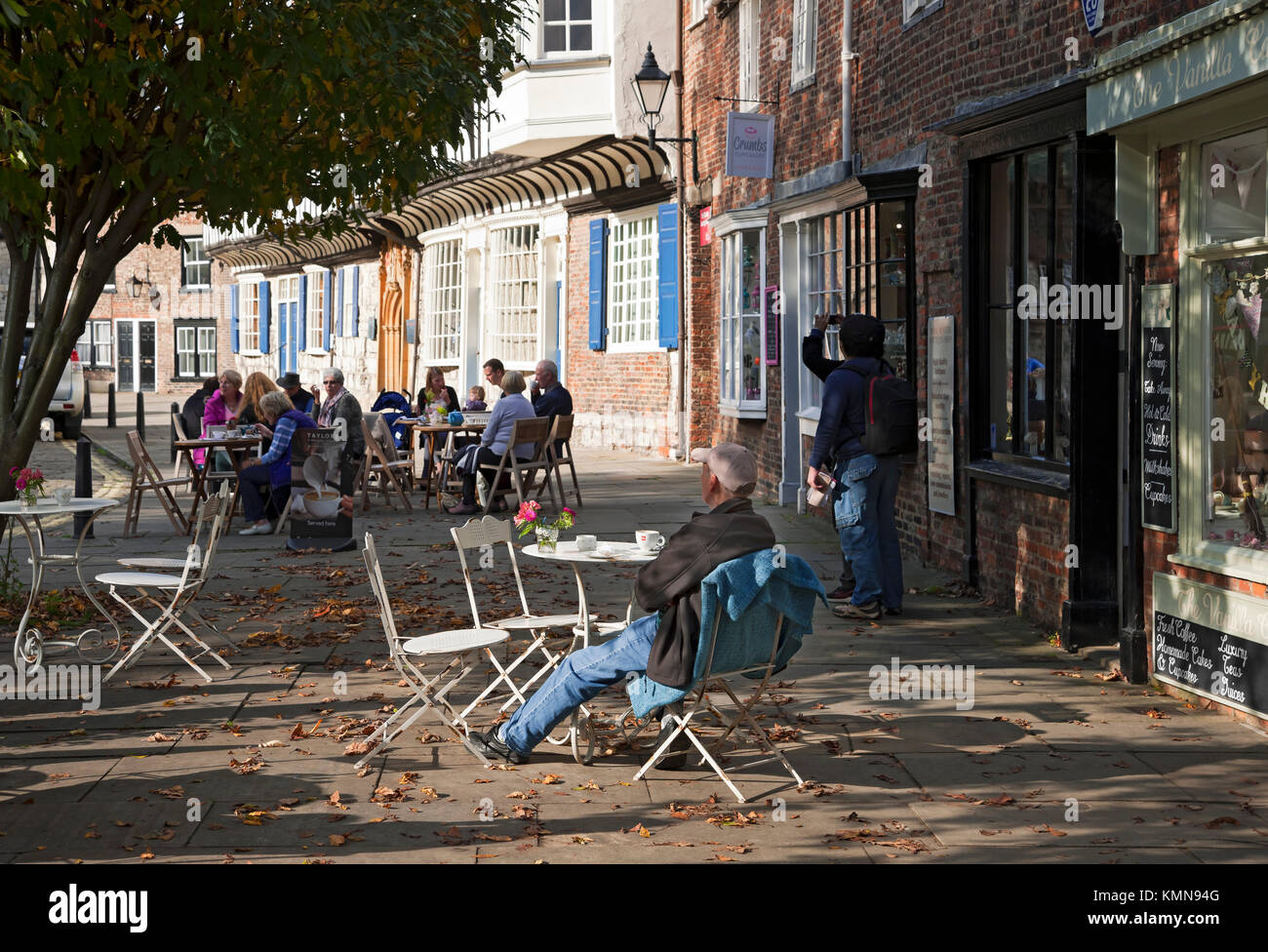 People sitting sat outside at outdoor pavement cafe tables in the city centre York North Yorkshire England UK United Kingdom GB Great Britain Stock Photo