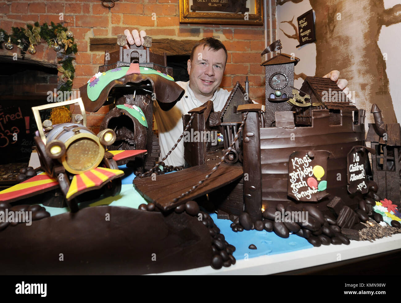 Ashley McCarthy, the chef and owner of Ye Old Sun Inn in Colton near York, with a chocolate tableau featuring scenes from Chitty Chitty Bang Bang that he has created to raise funds for the Martin House Children's Hospice near Leeds. McCarthy's chocolate artworks have raised thousands of pounds for the hospice over the past thirteen years. This year's effort took over 60 hours of melting, sticking and shaping 25kg of edible chocolate. Stock Photo