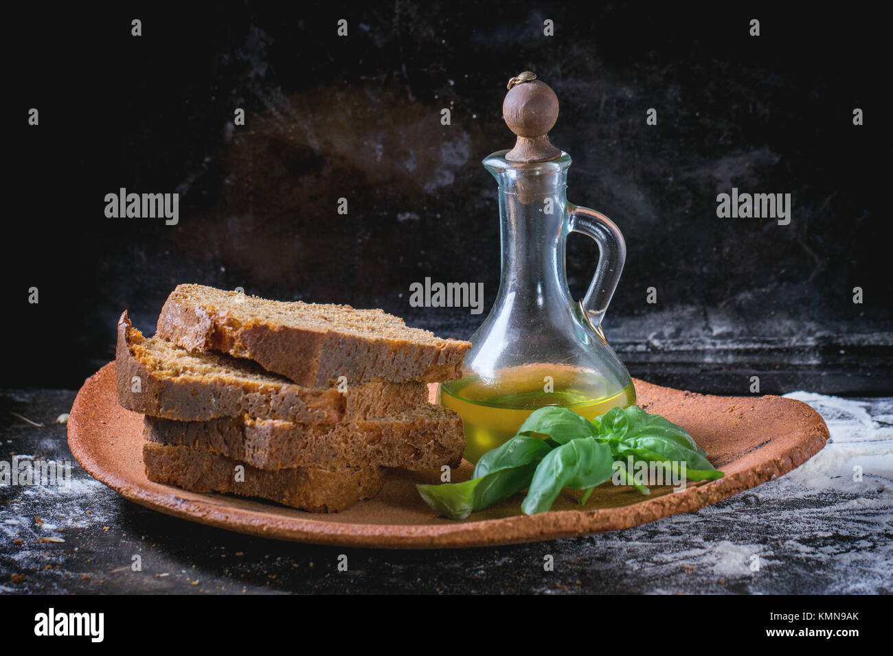 Clay plate woth sliced homemade rye bread, bottle of olive oil and