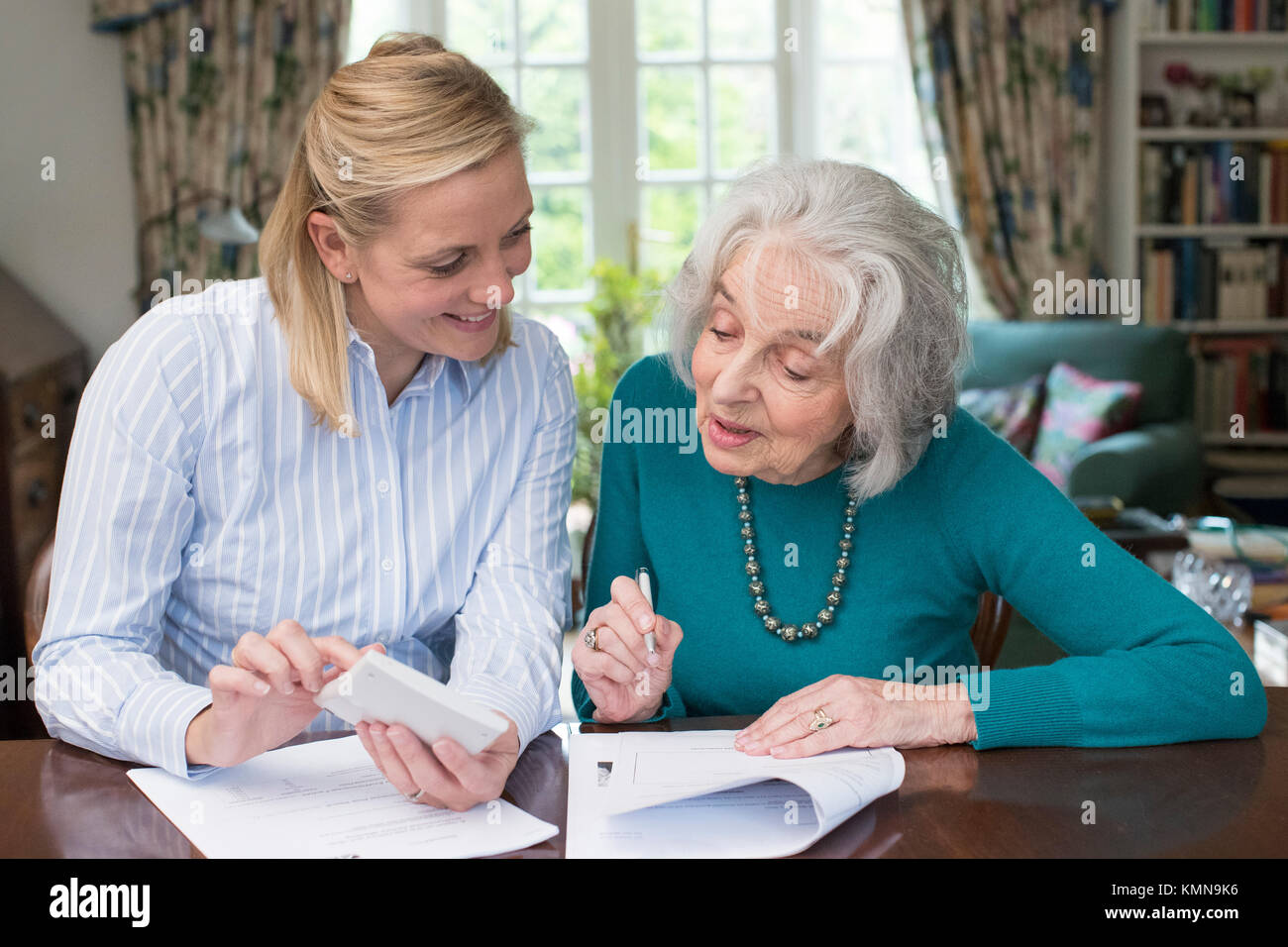 Woman Helping Senior Neighbor With Paperwork Stock Photo
