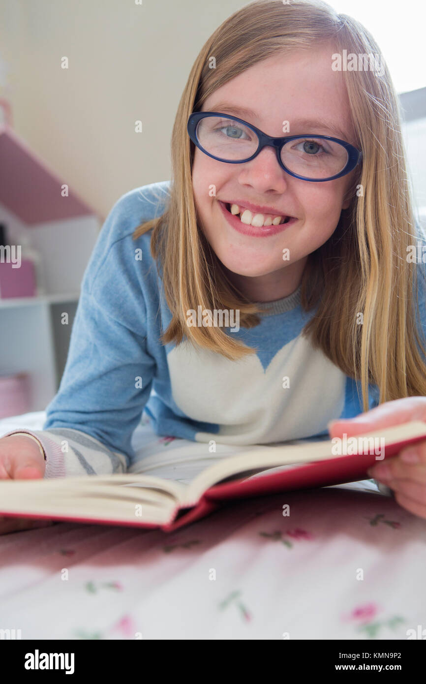 Young Girl Lying On Bed Reading Book Stock Photo