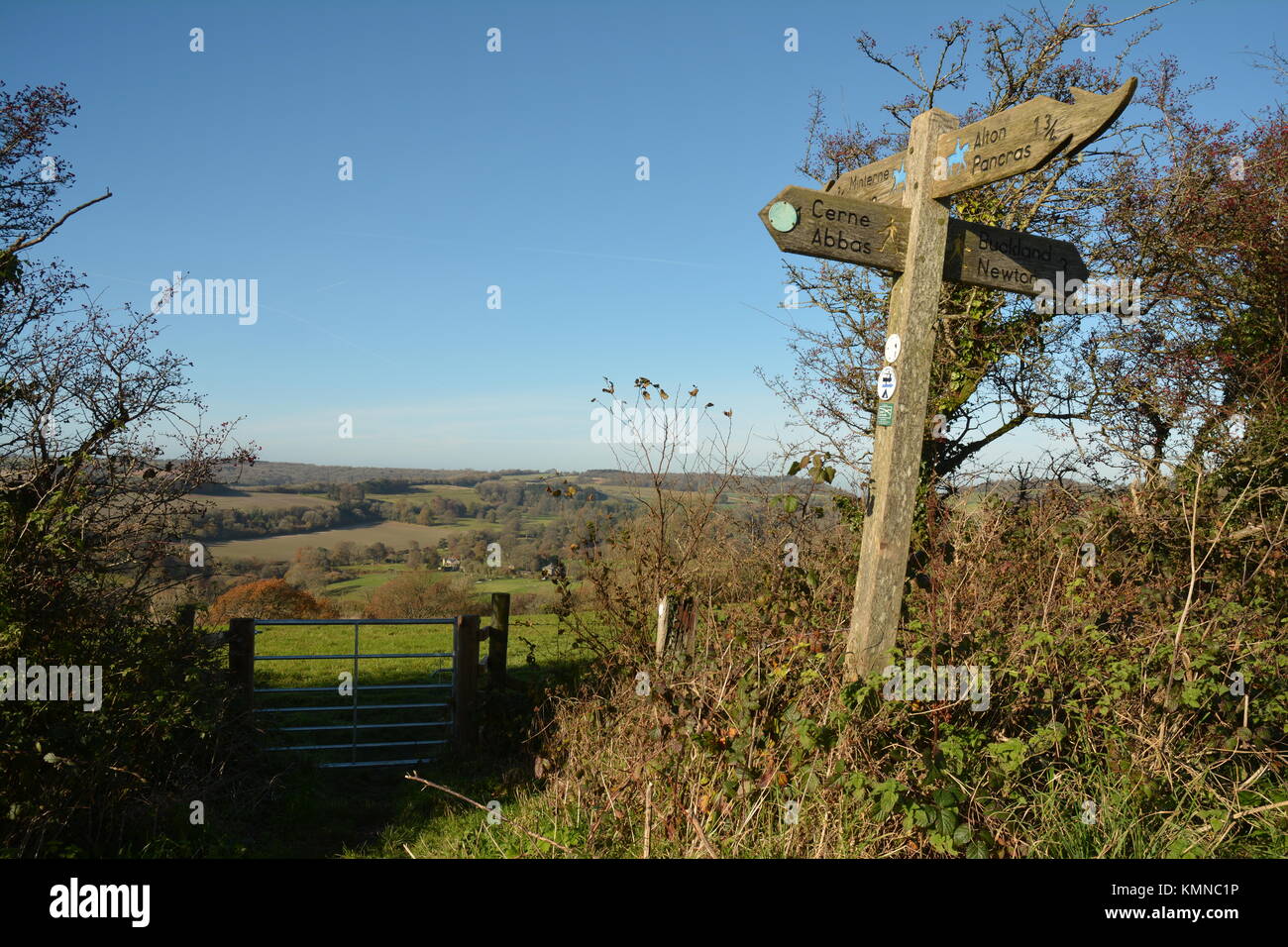 View over field gate and country signpost Stock Photo - Alamy