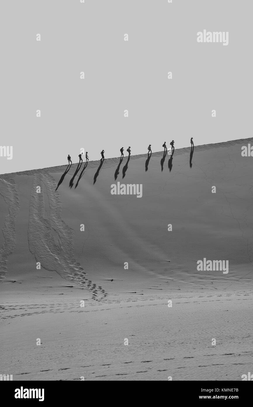 Tourists climbing a dune in the Namibian desert at Dead Vlei Stock ...