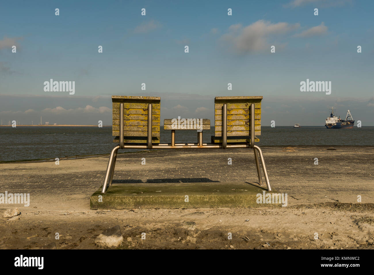 Back view of a wooden bench overviewing the water and ships passing by Stock Photo