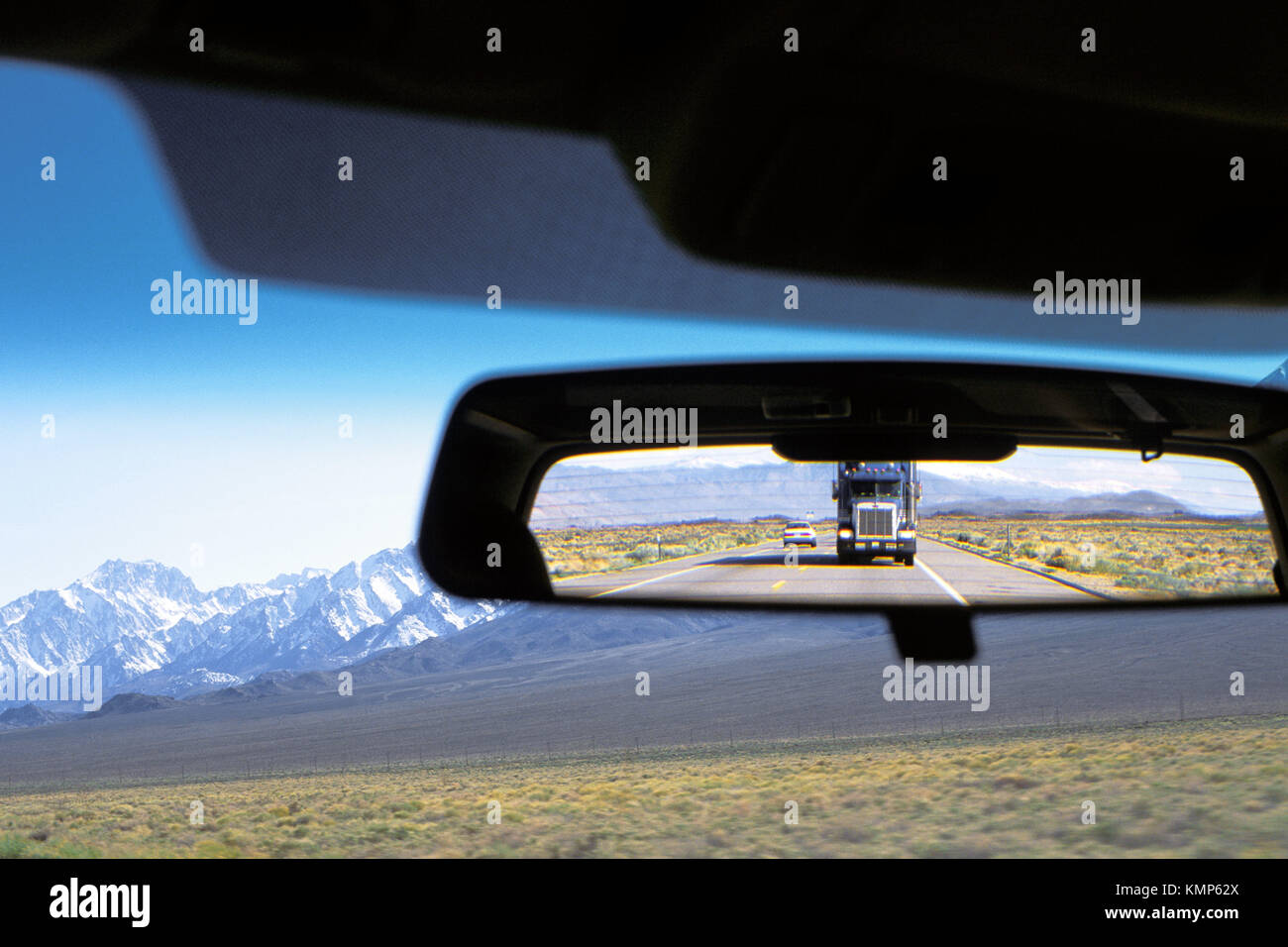 View from inside of a car with rearview mirror displaying highway