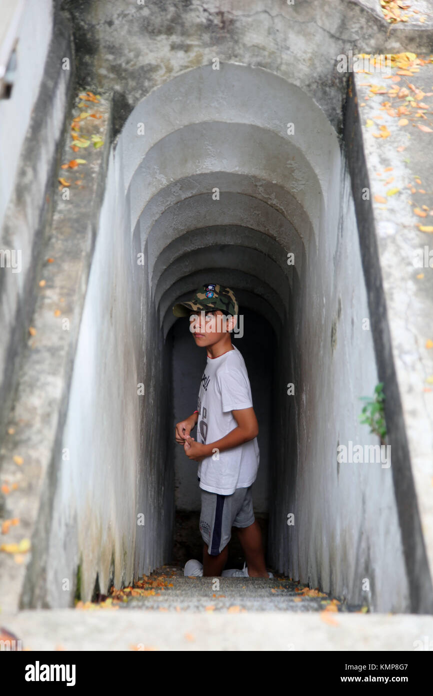 Young asian boy looking at camera while walking down a corridor with steps Stock Photo