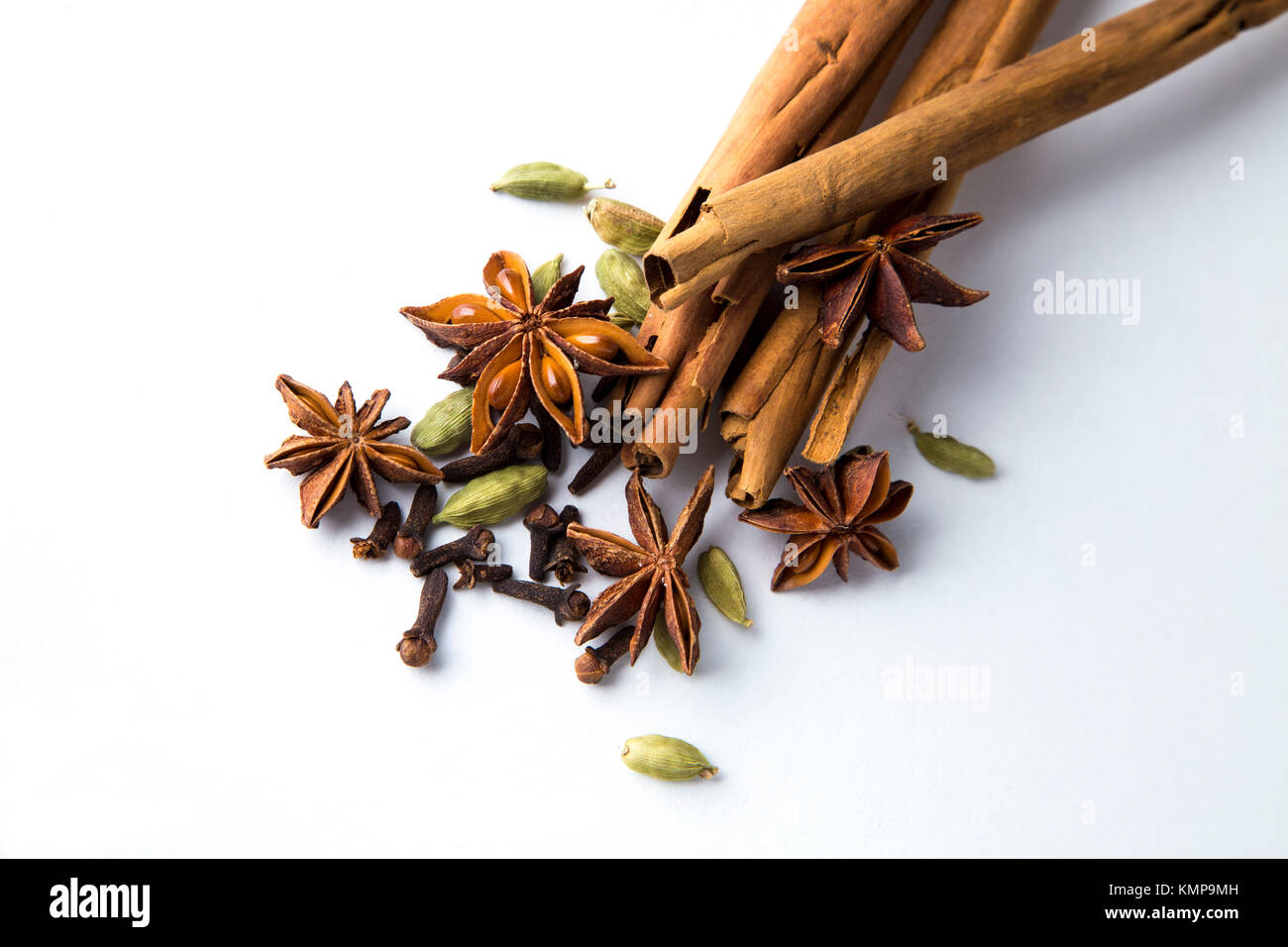 Aromatic and warming dried ayurveda spices (cinnamon, star anise, cardamom, cloves) on a white background Stock Photo