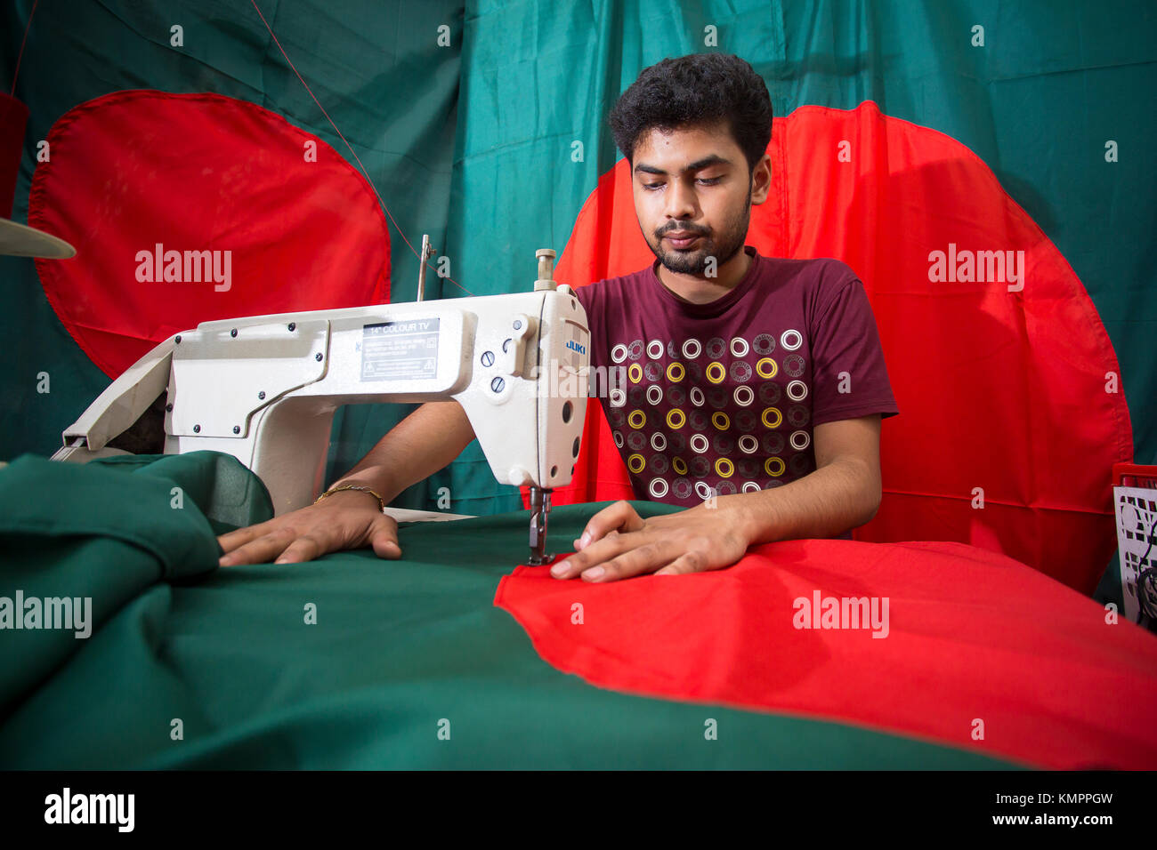 Dhaka, Bangladesh. 09th Dec, 2017. Victory day is a national holiday in Bangladesh celebrated on December 16 to commemorate the victory of the Allied forces High Command over the Pakistani forces in the Bangladesh Liberation War in 1971. A young tailor sewing cloth and making Bangladeshi national flags for selling Upcoming 16 December events. Credit: Jahangir Alam Onuchcha/Alamy Live News Stock Photo