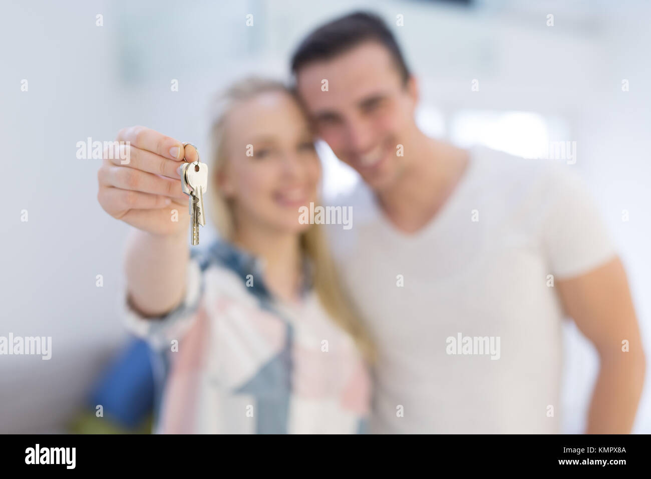 Happy smiling young couple hugging while showing a keys of their new ...
