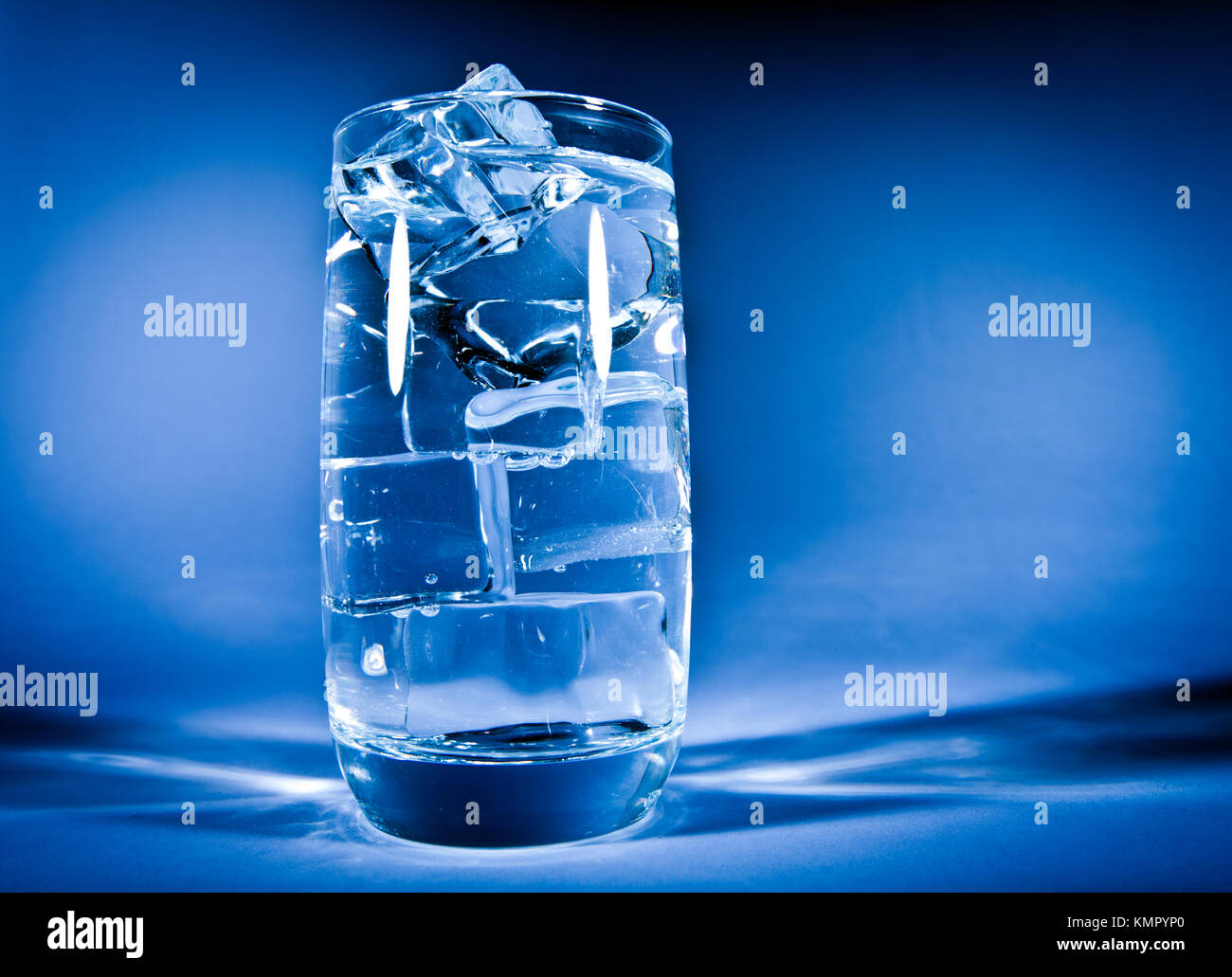 Glass of water with ice on a dark blue background Stock Photo - Alamy