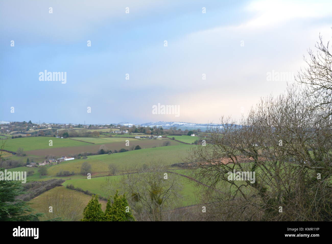 Winter country view from hill side across trees towards fields and open countryside with snow filled sky in South Herefordshire England UK Stock Photo
