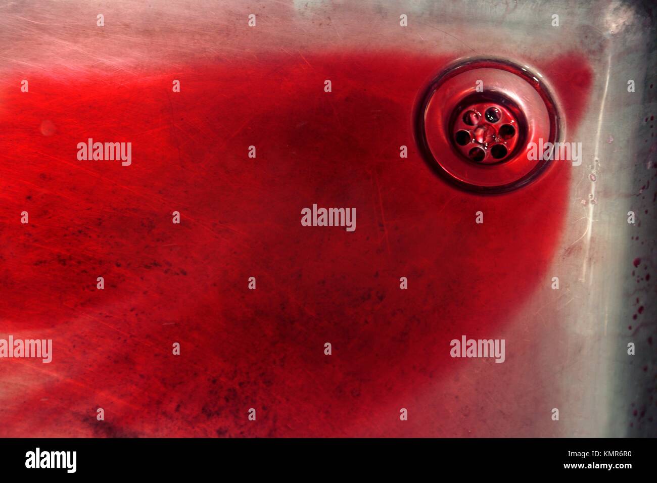 Blood in vivid red in a swtailess steel sink, murder metaphor Stock