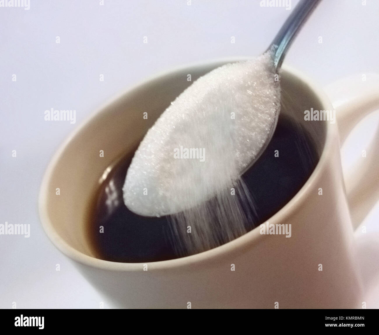 Teaspoon of sugar being poured into cup of coffee Stock Photo Alamy
