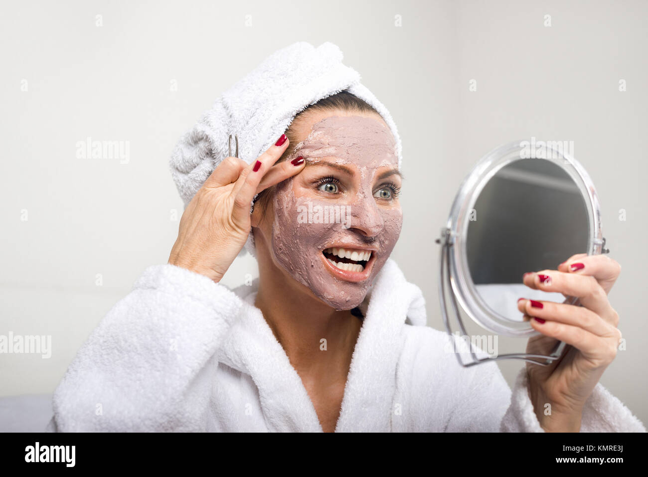 Woman Putting Cosmetic Mask On Her Face Looking In Round Mirror In Her Other Hand Shot Close Up 