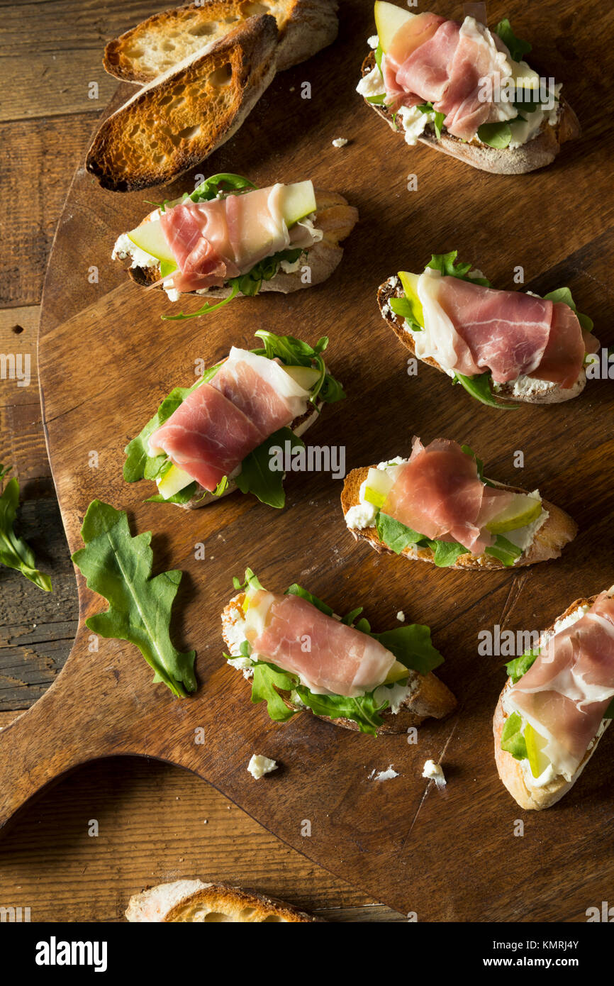 Homemade Prosciutto Pear Cheese Crostini with Arugula Stock Photo