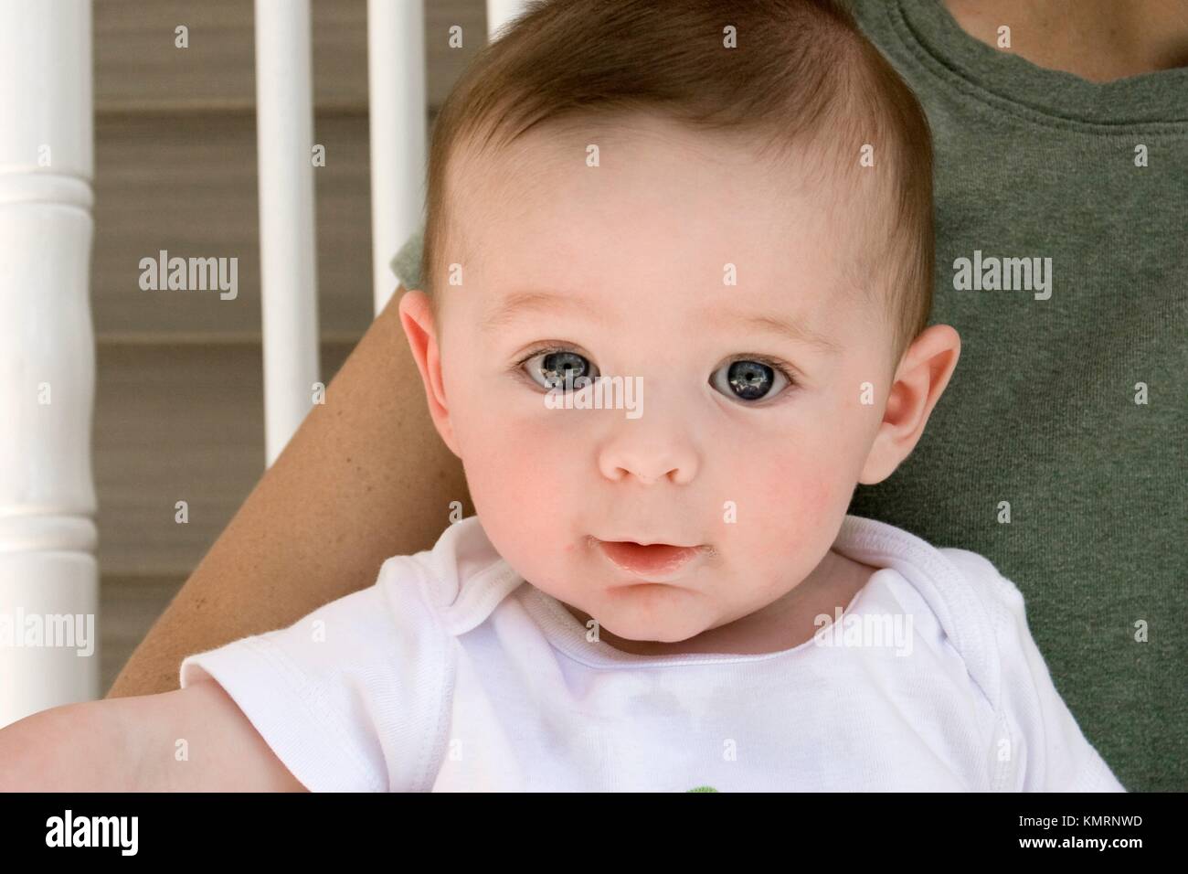 5month old baby boy sitting in his Mother´s lap in a rocking chair on