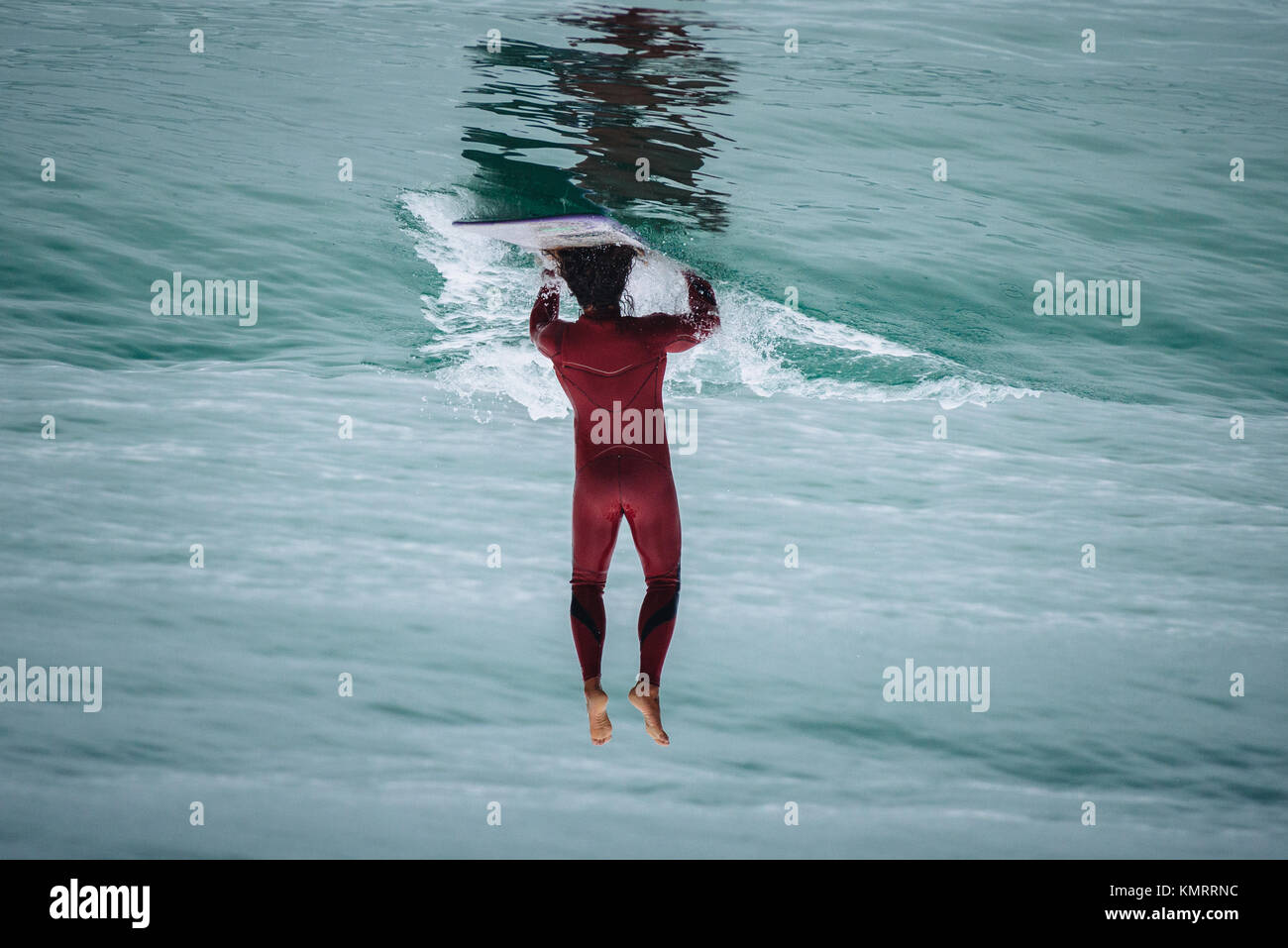 Surfer doing a head and hand stand on a surfboard. Image rotated for