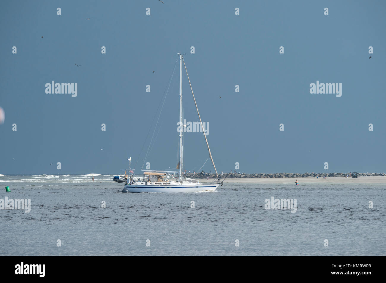Sailboat motoring into Ponce Inlet Stock Photo