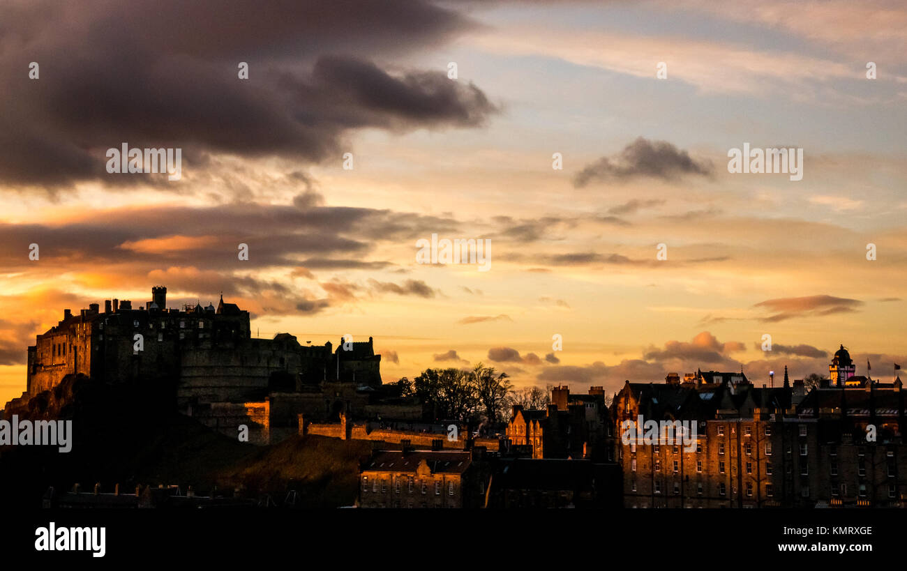 Colourful sunset with Edinburgh Castle rock outcrop and Royal Mile silhouetted against orange sky at dusk, Edinburgh, Scotland, UK Stock Photo