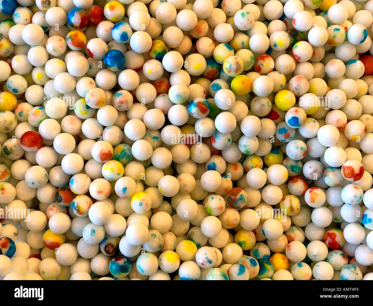 Close up on small white gum balls with color splashed on them. Stock Photo