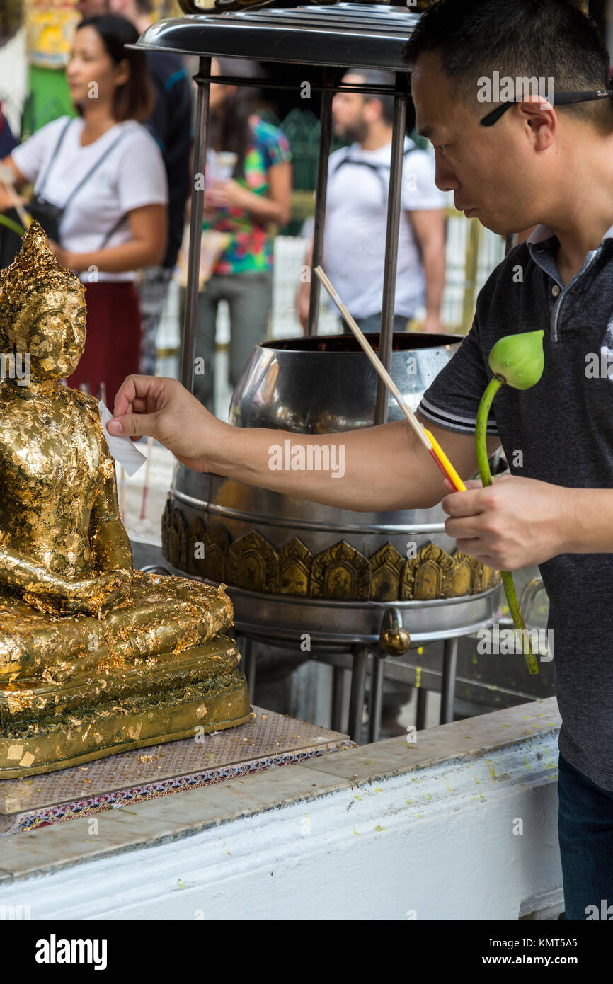 Bangkok, Thailand.  Worshipers Placing Gold Leaf on Buddha Statue, Royal Grand Palace Compound. Stock Photo