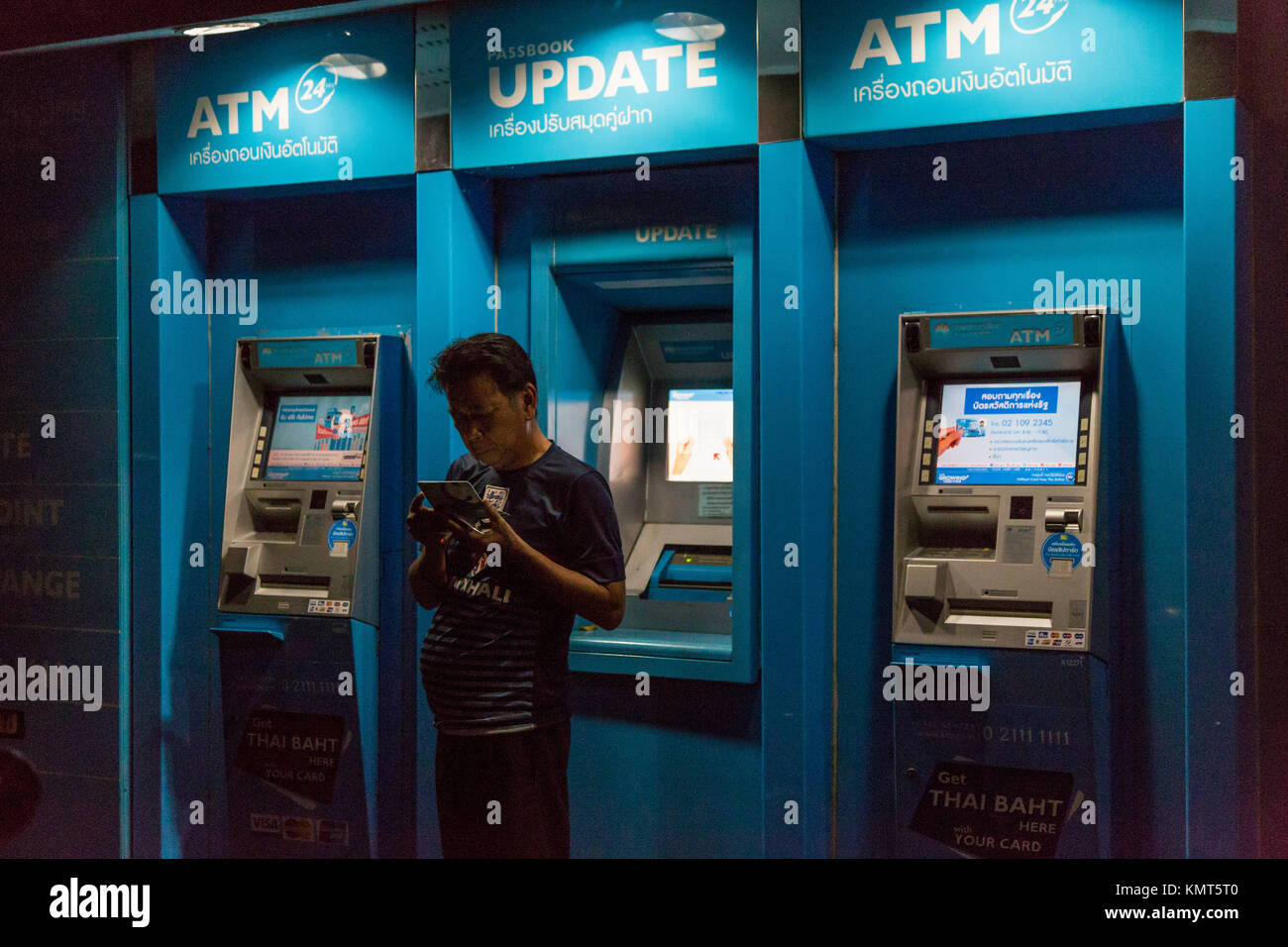 Bangkok, Thailand.  Nighttime Customer at ATM Machine. Stock Photo