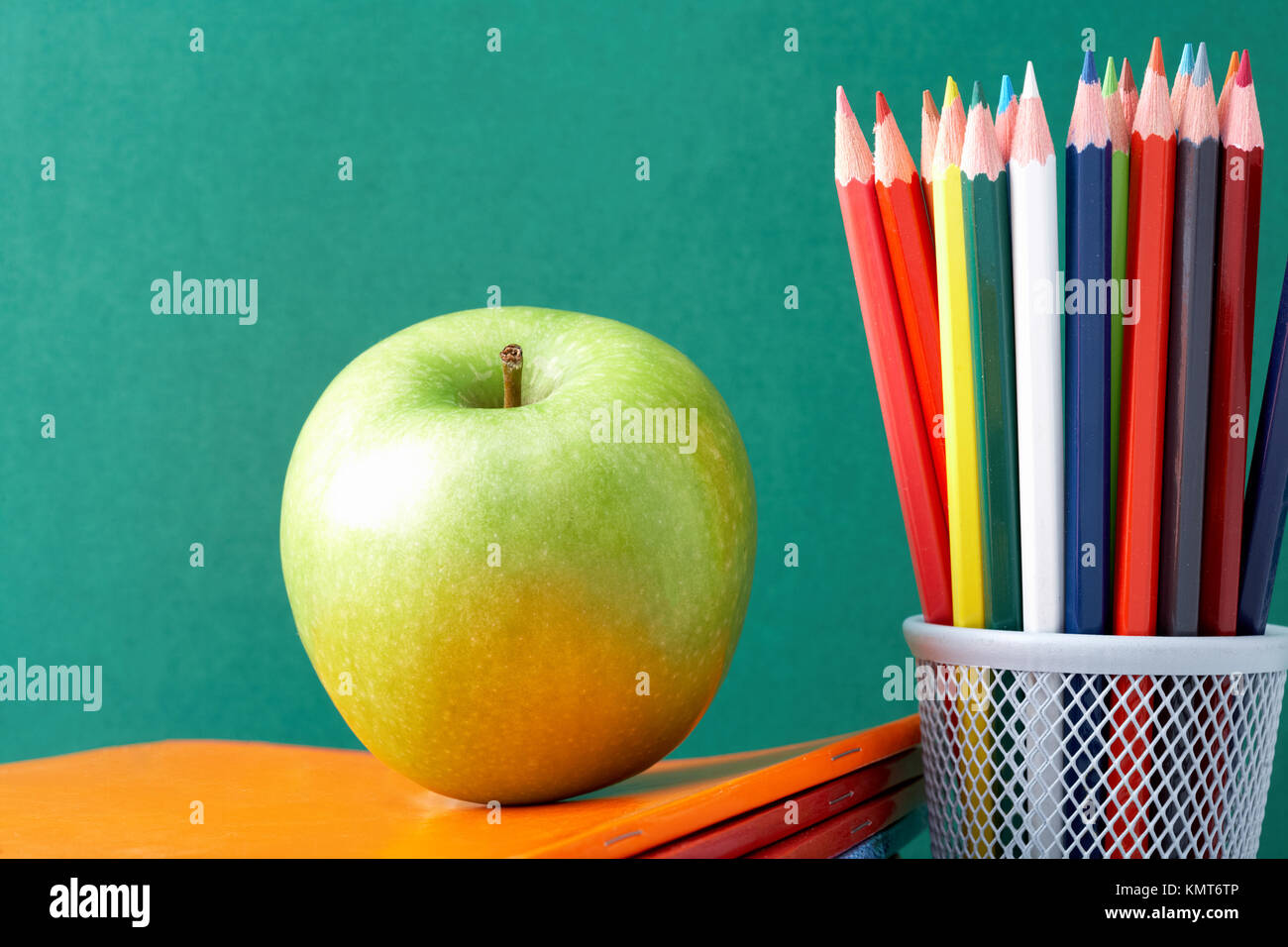 Image of crayons and green apple against blackboard Stock Photo